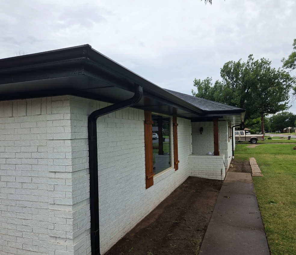 New black gutter on the corner of a white brick house