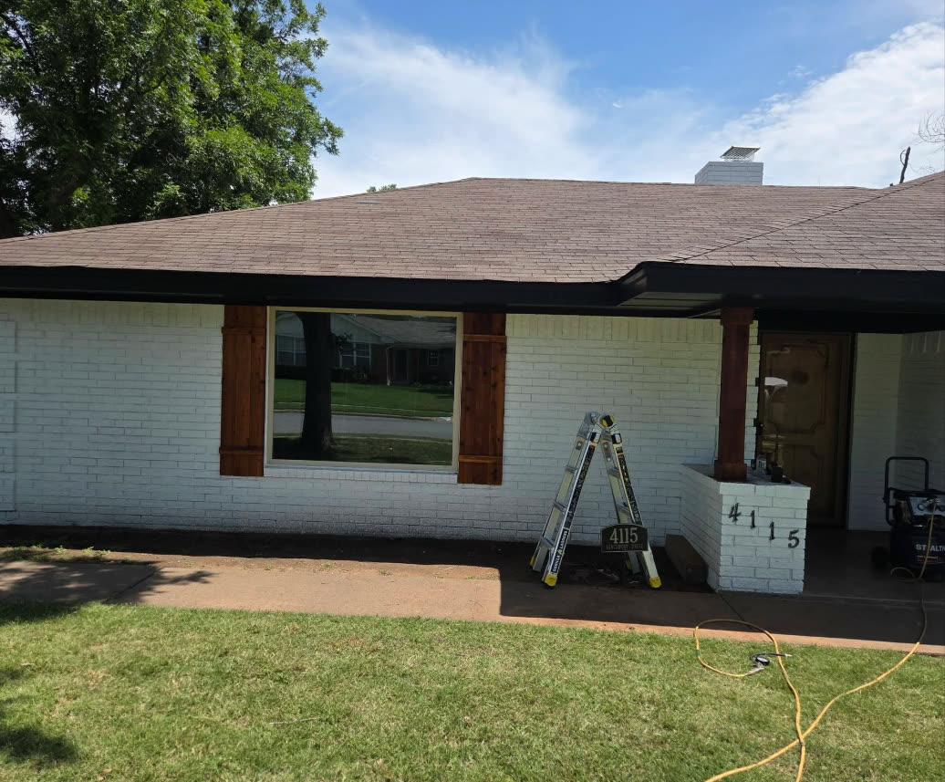 White brick house with a new dark roof and wood shutters