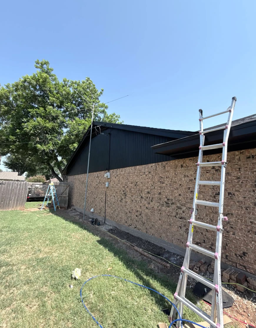 Ladder against a brick wall under a new roof edge